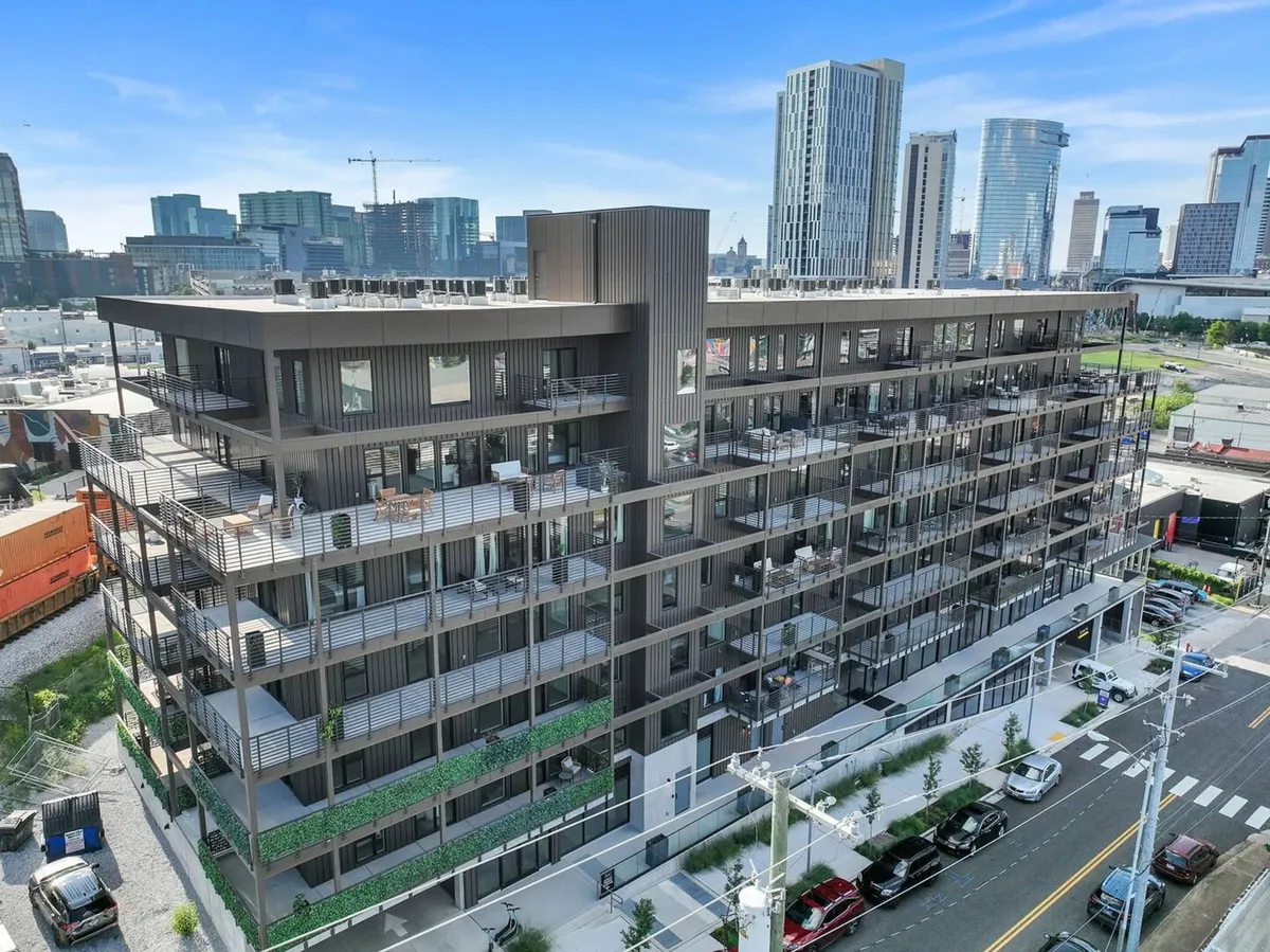 A modern apartment building with balconies featuring seating and a vibrant cityscape in the background. The image conveys urban energy and proximity to Nashville’s attractions, emphasizing accessibility and the flexibility of downtown stays.